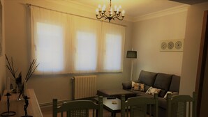 A living room with a sofa, two chairs, a coffee table, a radiator, and a chandelier.