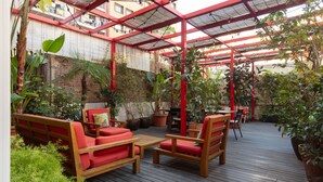 An outdoor patio with wooden furniture and potted plants. - Hotel Praktik Garden (Barcelona)