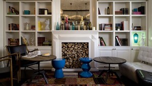 A library with bookshelves, a fireplace, and seating areas. - Hotel Praktik Garden (Barcelona)