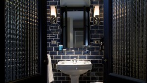 A bathroom with a white pedestal sink, a mirror, and a towel rack. - Hotel Praktik Garden (Barcelona)