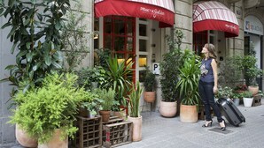 A hotel entrance with large potted plants and red awnings. - Hotel Praktik Garden (Barcelona)