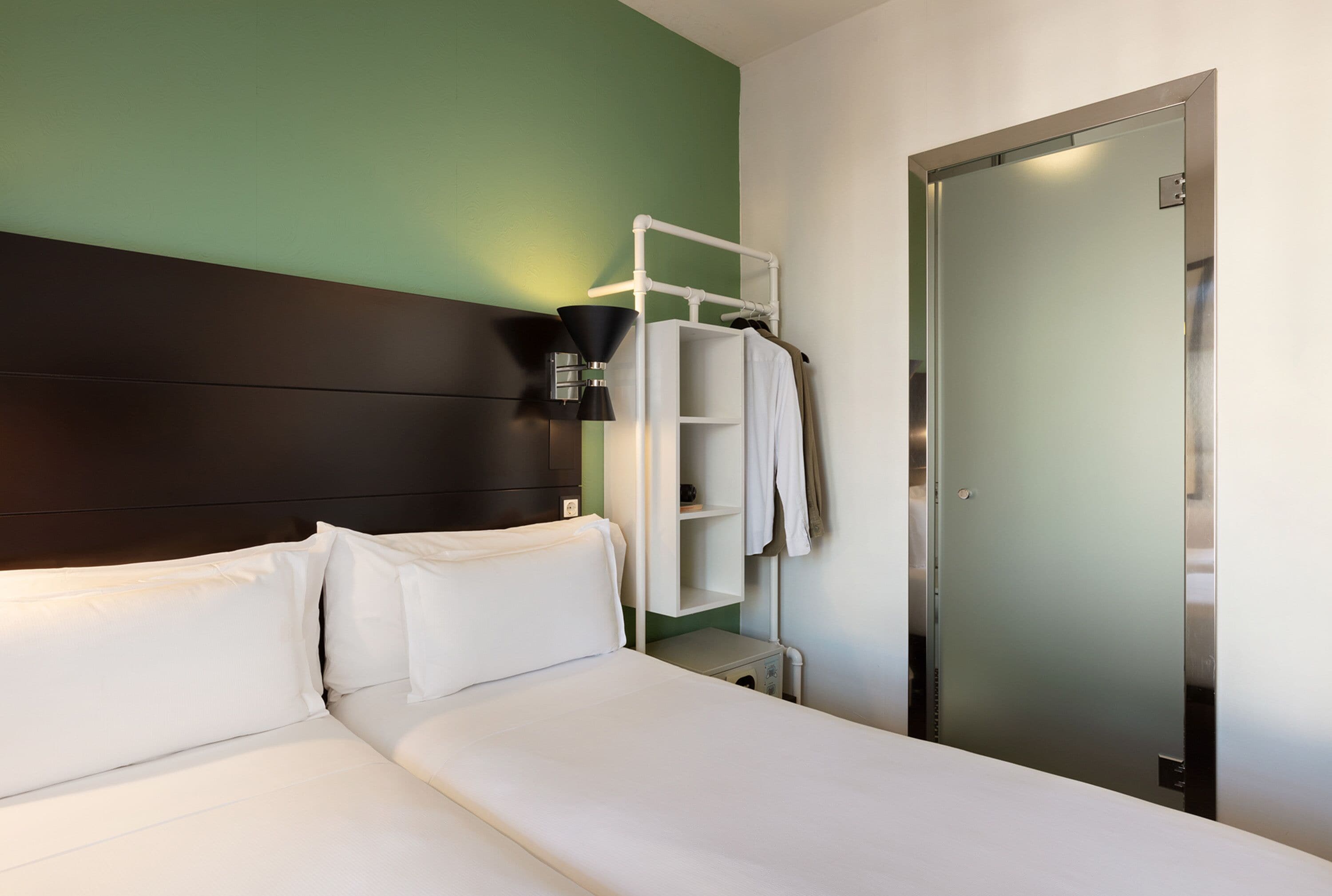 Une chambre d’hôtel avec un lit, une armoire, une étagère et une porte.