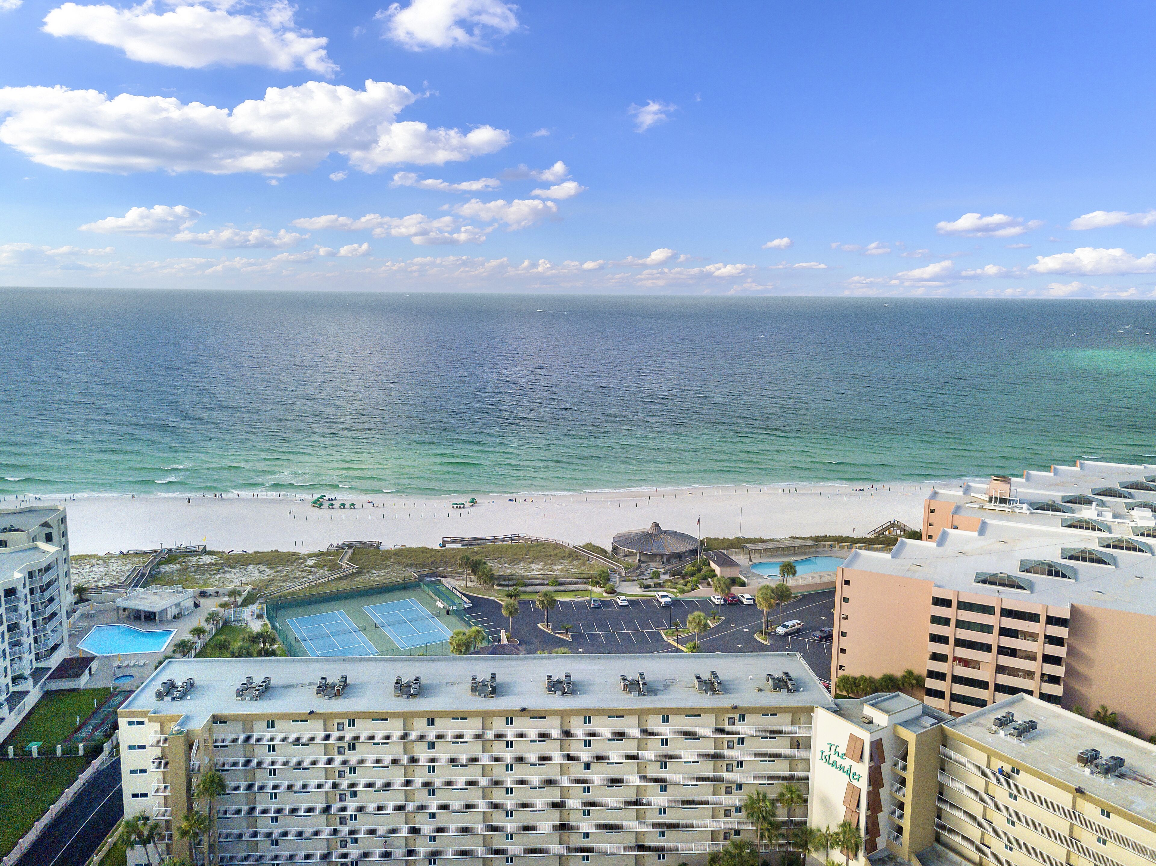 A hotel with a rooftop pool, a beach view, and a parking lot.