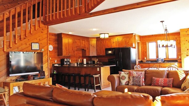 Un interior acogedor de cabaña con sala de estar, cocina y comedor.