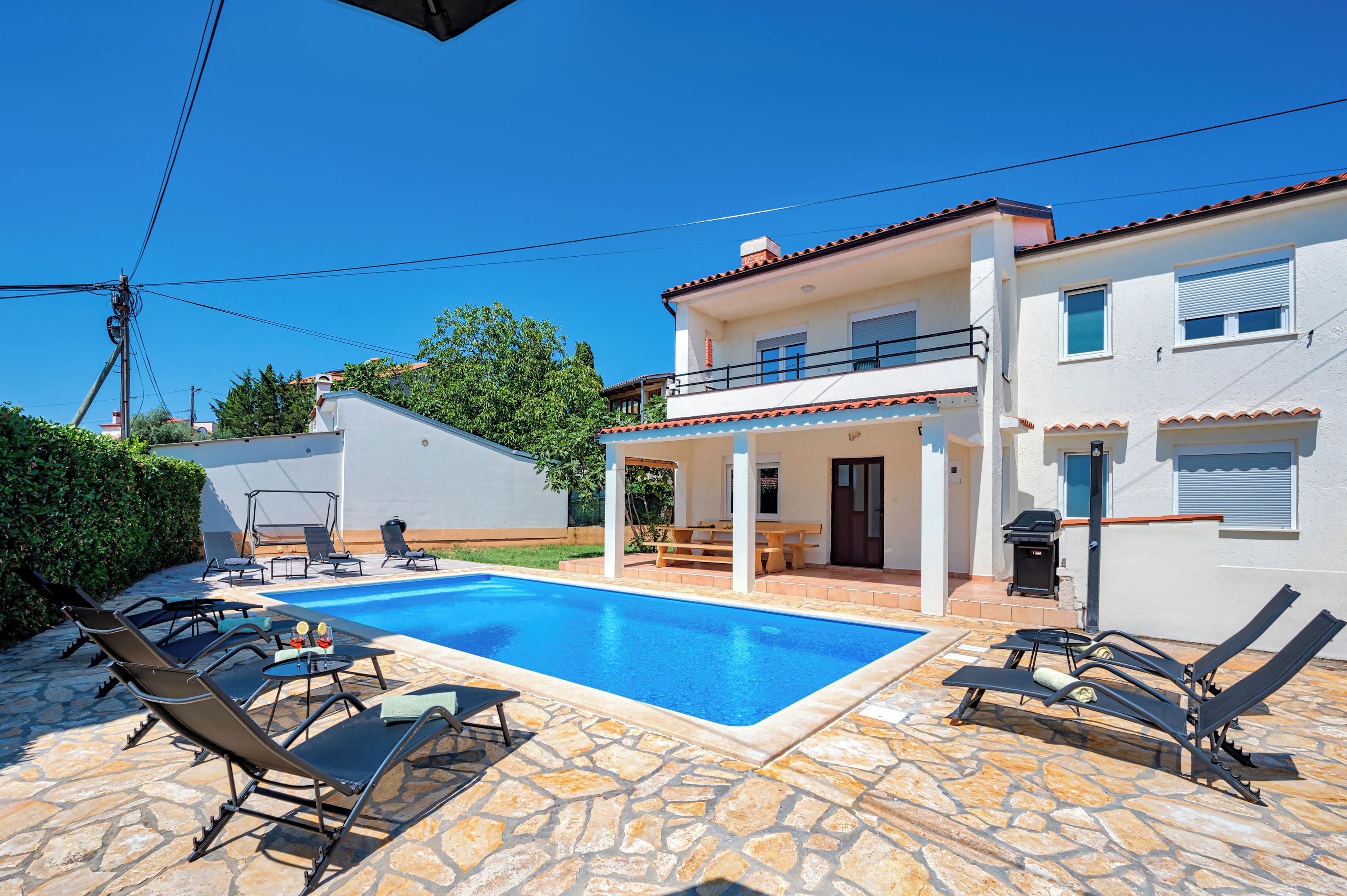 Une maison à deux étages dotée d’une piscine, d’un espace salon extérieur et d’un patio couvert.