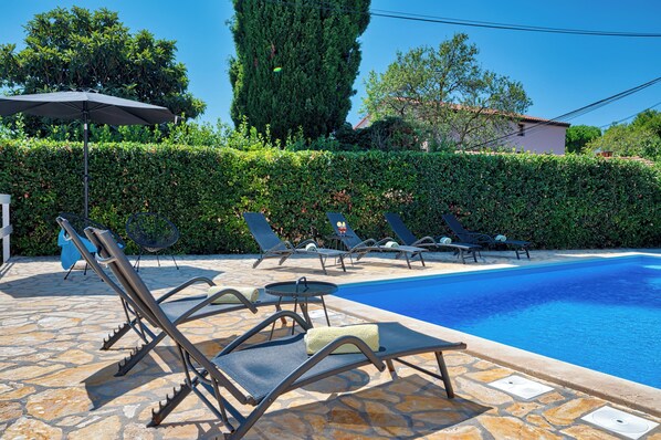 A pool area with lounge chairs and a stone floor. - House with pool, large garden and good location in Medulin (Medulin)