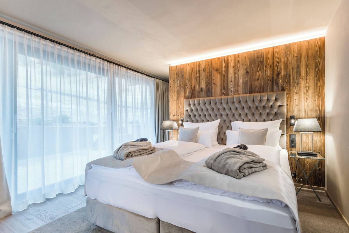 Una habitación de hotel moderna con una cama grande, un panel de pared de madera y vistas al exterior.