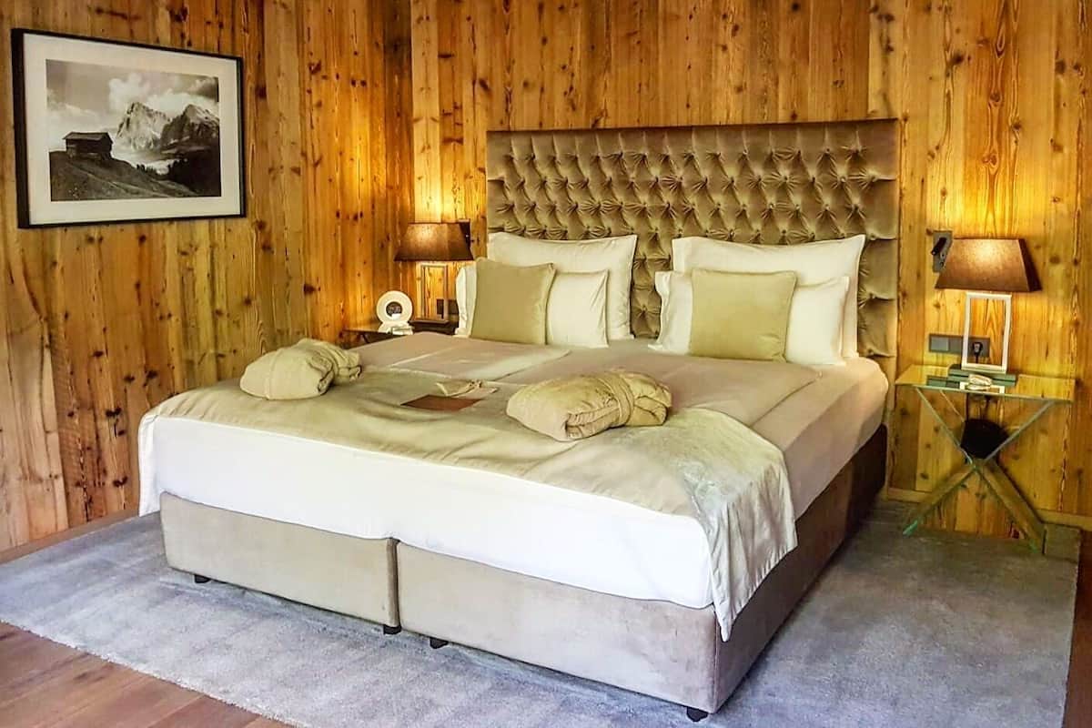 Un dormitorio con una cama grande, paneles de madera en las paredes, un cuadro enmarcado y dos lámparas de noche.