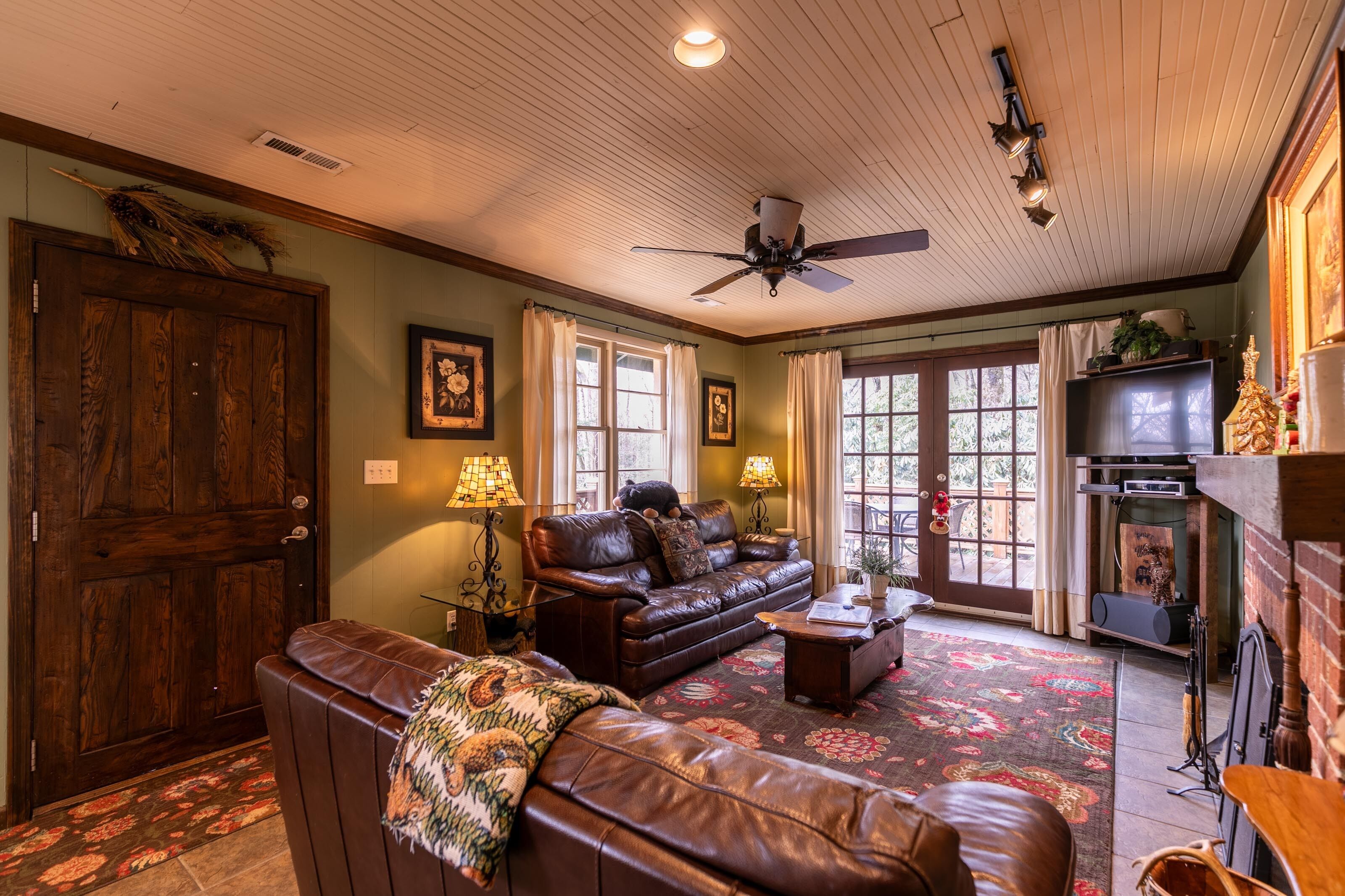 A cozy living room with a leather sofa, a wooden door, and a fireplace.