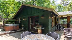 A cozy outdoor patio with a hot tub, grill, and seating area. - Bear Bungalow - 1 mile from Main Street Blowing Rock! Hot Tub - Pet Friendly - Fenced In Yard (Blowing Rock)