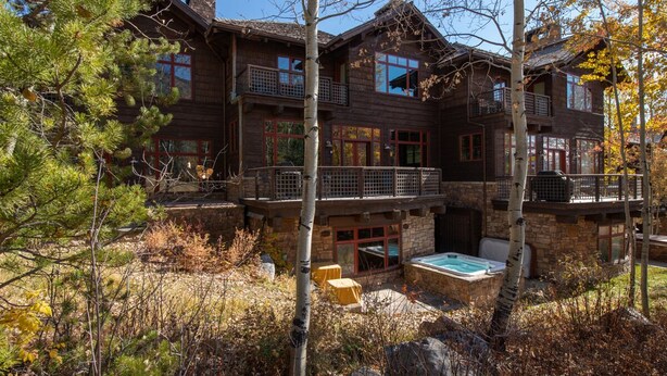 Une grande cabane en bois dotée de plusieurs balcons et d’un jacuzzi dans le jardin.