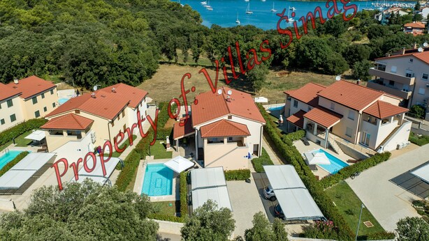 Zona residencial con varias casas, cada una con piscina y techo de tejas rojas.