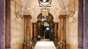 Un vaste hall d’entrée doté d’un sol en marbre, de colonnes richement décorées et d’un lustre central.