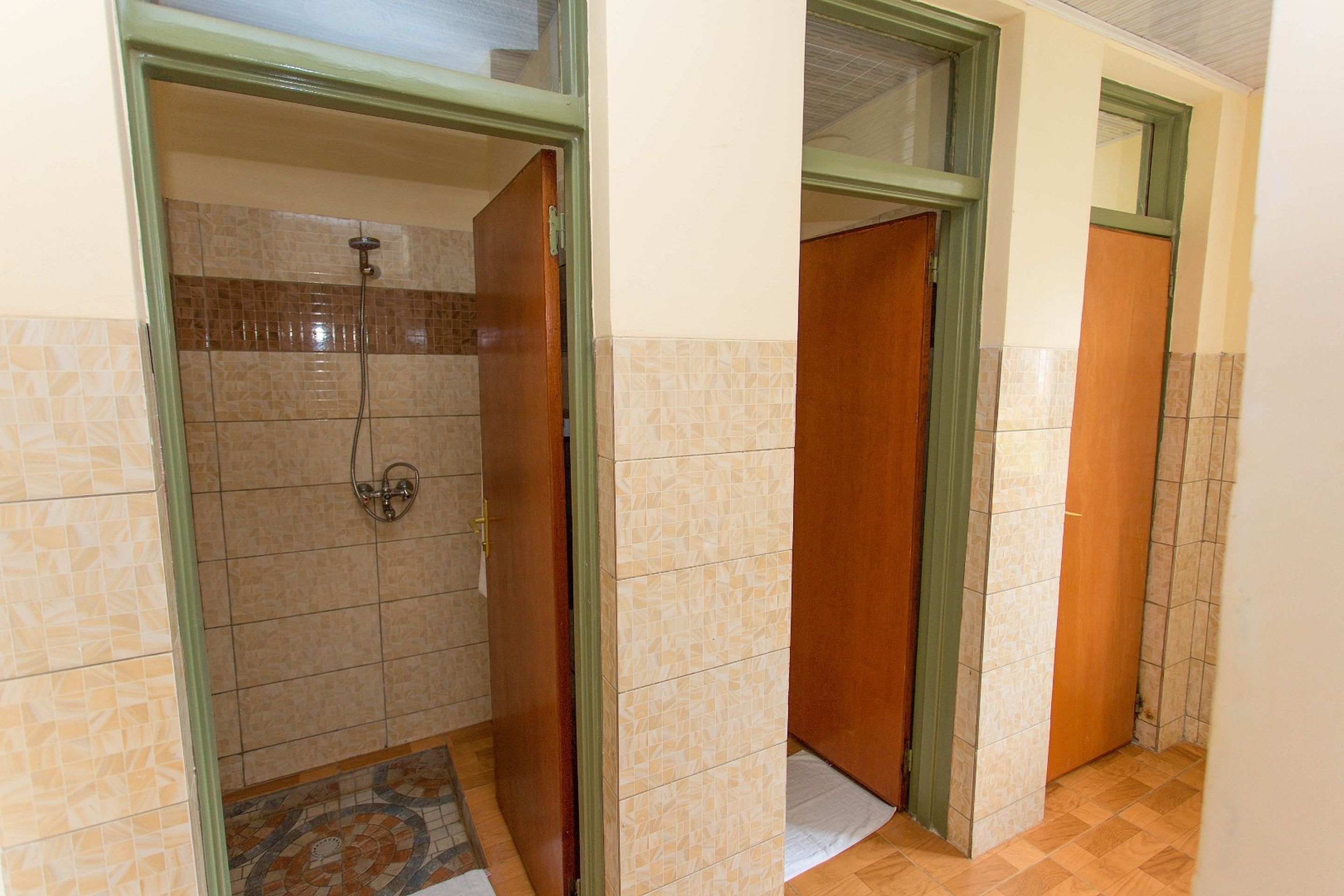 Een badkamer met een douche, betegelde wanden en houten deuren.