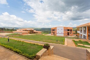 A modern building complex with multiple structures, a well-maintained lawn, and a clear sky. - Cenetra Hotel (Kigali)