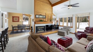 A spacious living room with a fireplace, comfortable seating, and large windows. - Spacious Centrally Located Condo in Quicksilver/Pool and Hot Tub Access (Keystone)