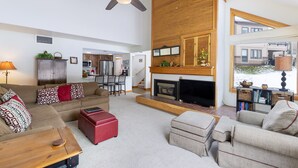 A spacious living room with a fireplace, a ceiling fan, and a view of the outside. - Spacious Centrally Located Condo in Quicksilver/Pool and Hot Tub Access (Keystone)