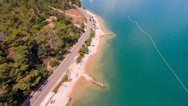 An aerial view of a coastal road with a beach, lined with trees and a few buildings. - Apartment with sea view and quiet Mediterranean ambience (Dobrinj, Krk)