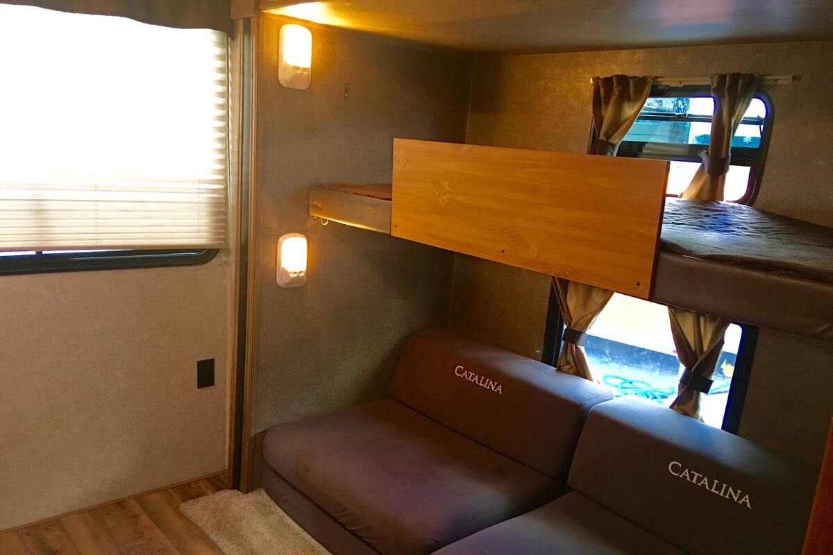 A cozy interior with a bunk bed, a cushioned seating area labeled 'CATALINA', and a window with curtains.