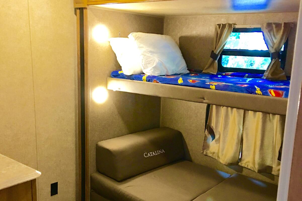 A compact bunk bed with a mattress labeled "CATALINA" and a small seating area below.
