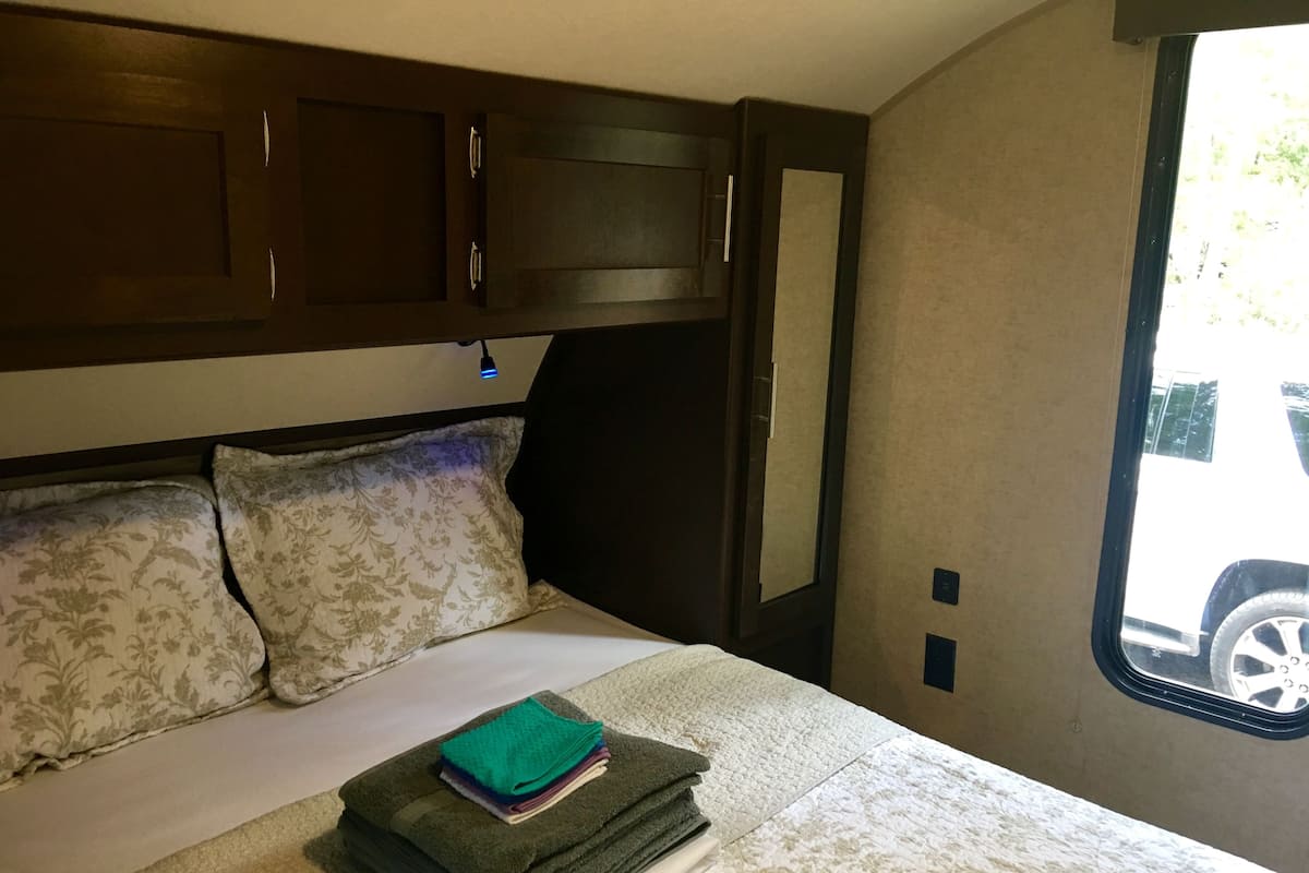 A bed with floral-patterned pillows and a neatly folded stack of towels.