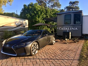 A black Lexus SUV parked in front of a Catalina RV. - Enduro RV Citrus Valley Resort (Clermont)