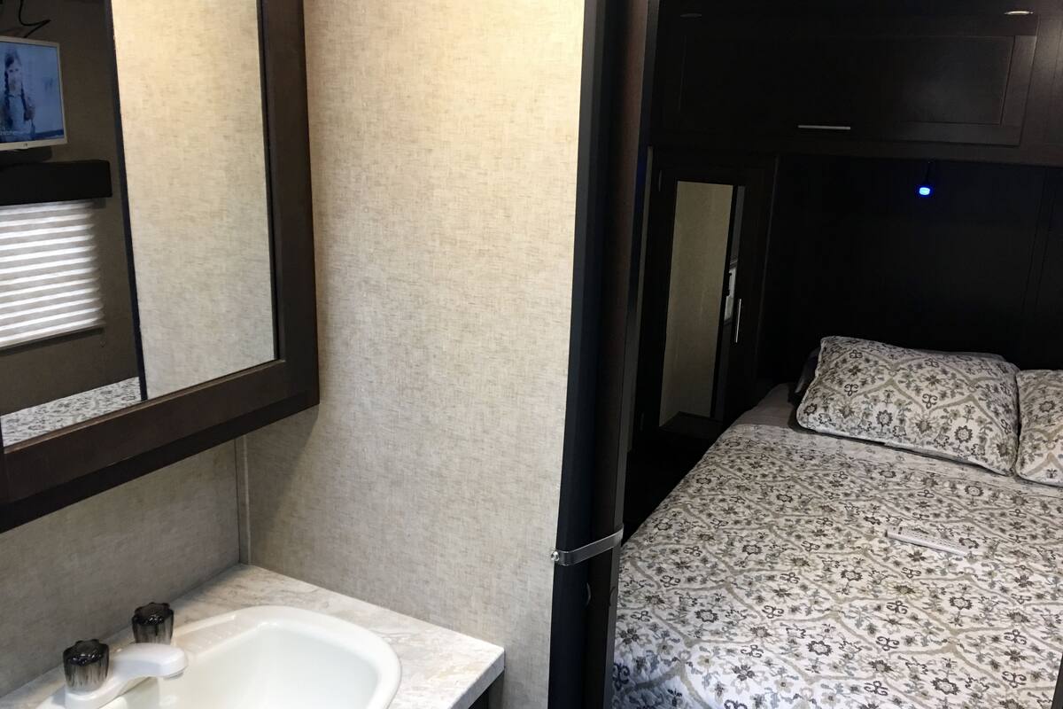 A compact bedroom with a bed, a bedside table, and a mirror.