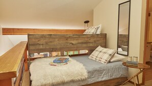 Ein Schlafzimmer im Loft-Stil mit einem Holzkopfteil, einem kleinen runden Tisch und einem Spiegel.