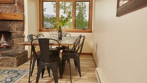 Ein Essbereich mit Kamin aus Stein, einem Holztisch und vier Stühlen.