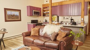 Ein gemütliches Wohnzimmer mit einer braunen Ledersofa, einem Holztisch und einem Essbereich mit Holztisch und -stühlen.