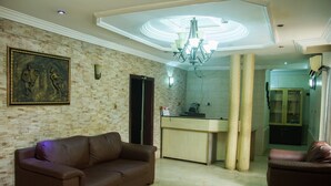 Una sala de estar con un sofá de cuero marrón, un comedor con una encimera de color claro y una cocina con armarios y un refrigerador.