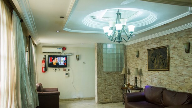 Una sala de estar con candelabro, sofás de cuero, televisor y pared de ladrillo.