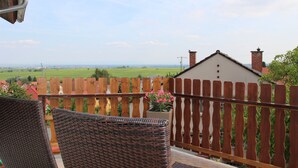 Un balcon doté de meubles en osier et offrant une vue sur un paysage rural.
