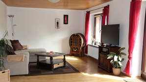 Un salon avec un canapé, une table basse, un téléviseur et une plante en pot.