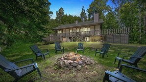 A lodge with a fire pit surrounded by chairs, a deck, and a staircase leading to a balcony. - A Comfortable & Spacious Retreat in the Powderhorn Village (Ironwood)