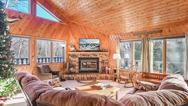 A cozy cabin interior with a fireplace, leather sofas, and a Christmas tree. - A Comfortable & Spacious Retreat in the Powderhorn Village (Ironwood)