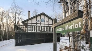 Chateau Merlot, a lodge with a prominent entrance and a large chimney, surrounded by snow and birch trees. - A Comfortable & Spacious Retreat in the Powderhorn Village (Ironwood)