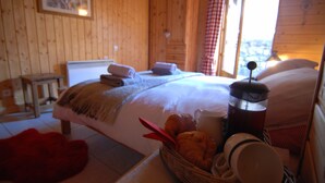 A wooden cabin bedroom with a bed, a basket of bread, and a coffee maker. - Ancienne Fromagerie, a unique chalet, beautifully renovated  in central Samoens  (Samoëns)