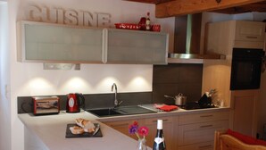 A modern kitchen with a built-in oven, a toaster, and a wine bottle on the counter. - Ancienne Fromagerie, a unique chalet, beautifully renovated  in central Samoens  (Samoëns)