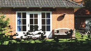 A brick building with a tiled roof, a white-framed window, and a bench outside.