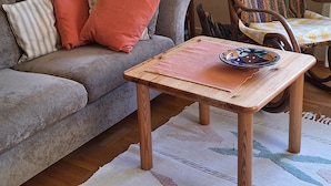 A cozy living room with a grey sofa, a patterned armchair, a wooden coffee table, and a bookshelf filled with books. - Experience nature, peace and quiet and Astrid Lindgren's world - Welcome to Småland (Mariannelund)