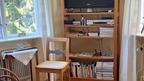 A cozy room with a wooden bookshelf filled with books, a television, and a chair. - Experience nature, peace and quiet and Astrid Lindgren's world - Welcome to Småland (Mariannelund)