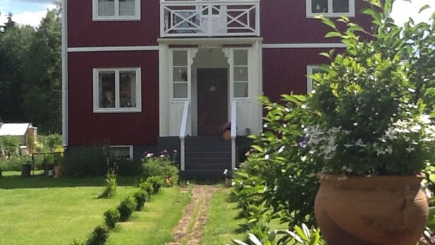 A two-story building with a central entrance, a small balcony, and a well-maintained lawn with a stone pathway leading to the entrance. - Experience nature, peace and quiet and Astrid Lindgren's world - Welcome to Småland (Mariannelund)