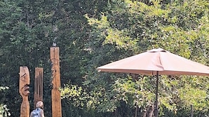 An outdoor seating area with a wooden table and chairs, a picnic table, and a large umbrella. - Experience nature, peace and quiet and Astrid Lindgren's world - Welcome to Småland (Mariannelund)