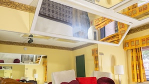 A hotel room with a large mirror, a bed with red and white bedding, a standing lamp, and a window with yellow curtains. - Luxe Inn and Suites (Dolton)