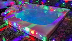 A rectangular bathtub with a faucet, surrounded by colorful lights reflecting on the water. - Luxe Inn and Suites (Dolton)
