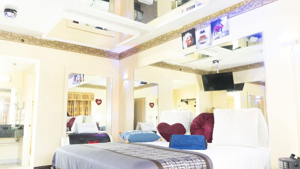 A hotel room with a large bed, a flat-screen TV, and a ceiling with recessed lighting. - Luxe Inn and Suites (Dolton)