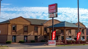 A hotel with a sign for Luxe Inn & Suites, a fenced parking area, and a nearby Taco Bell. - Luxe Inn and Suites (Dolton)