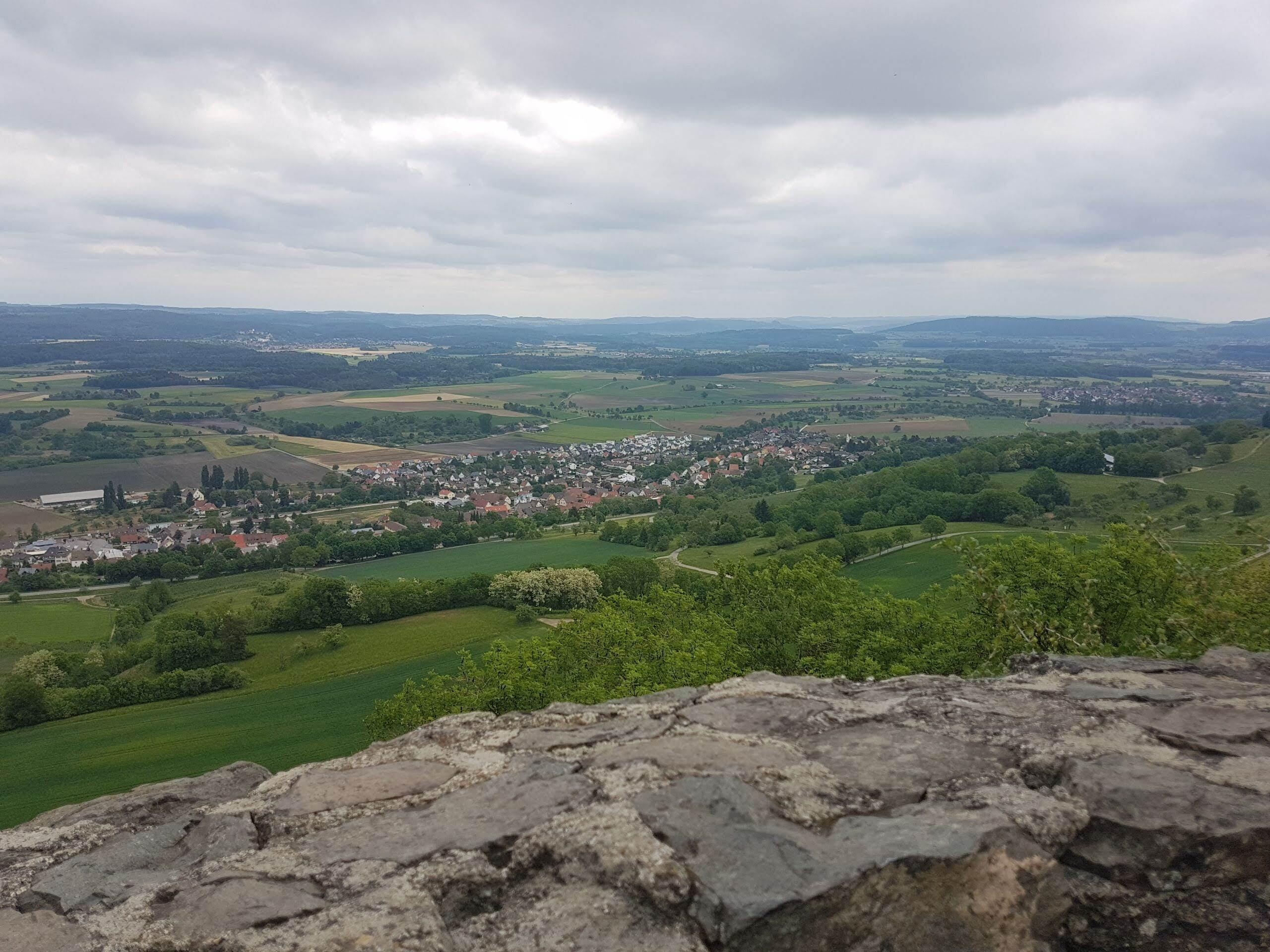 Ein weiter Panoramablick auf eine Stadt, die in einem Tal liegt, mit einer Steinmauer im Vordergrund.