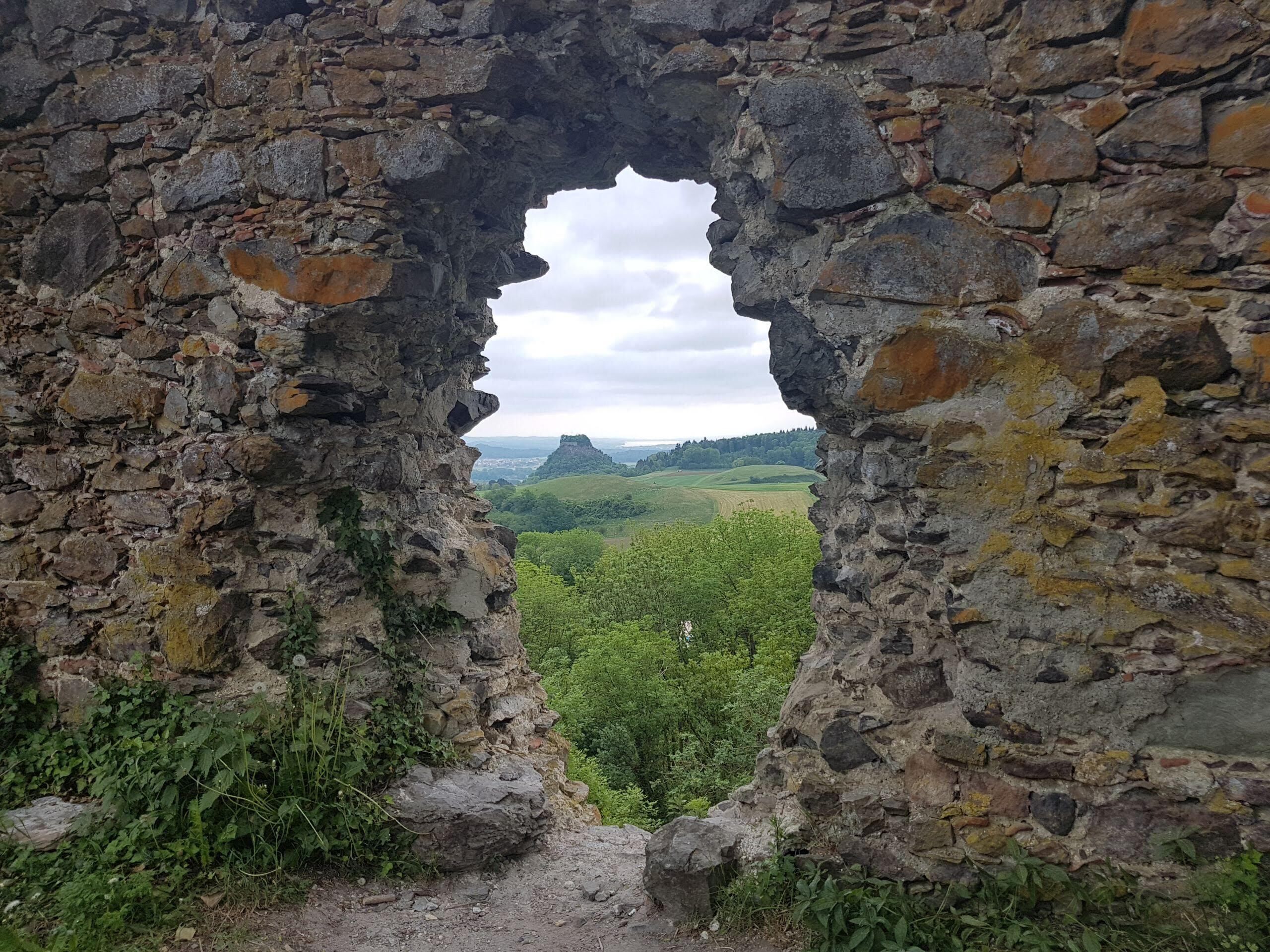 A stone archway leading to a lush green landscape.